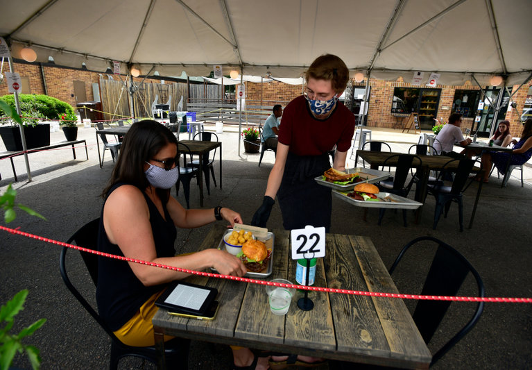 People dining outdoors wearing masks